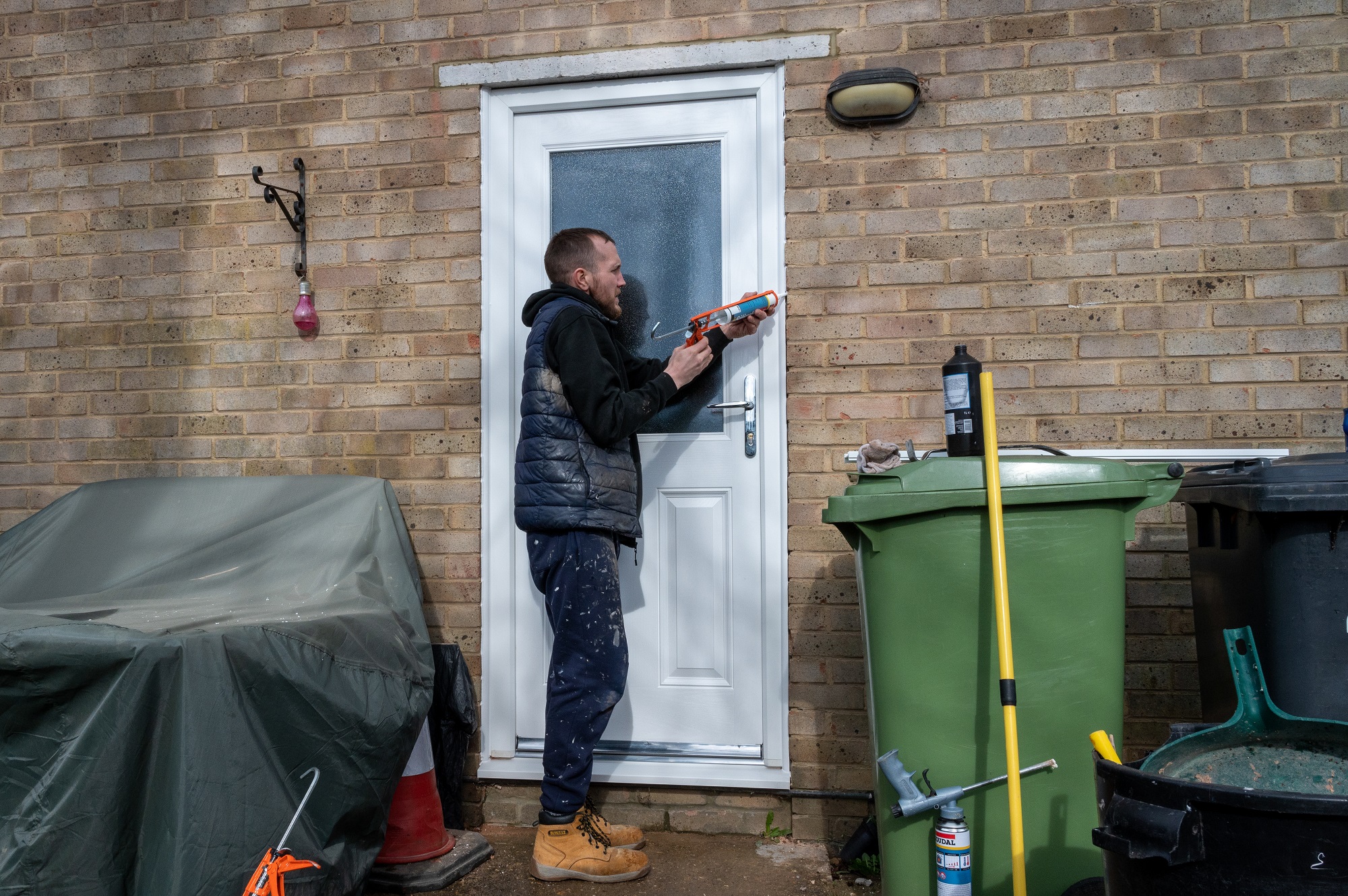 A tradesman fitting a new white front door to a house