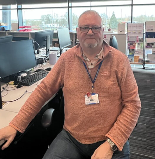 A male detective sitting at a desk in an office