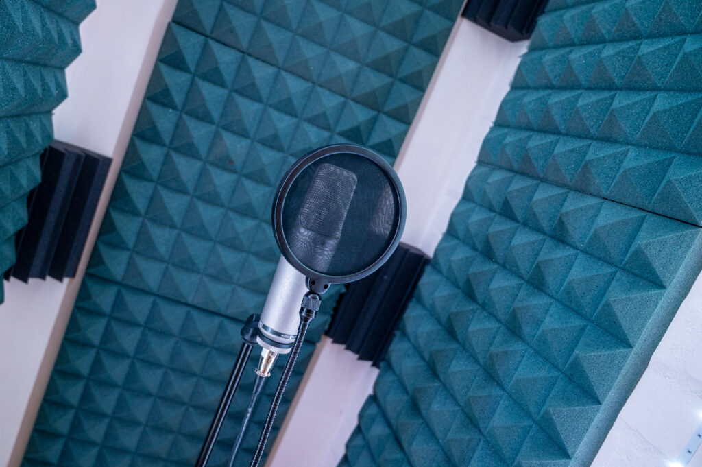 A microphone in a music studio with green sound proofing material in the background