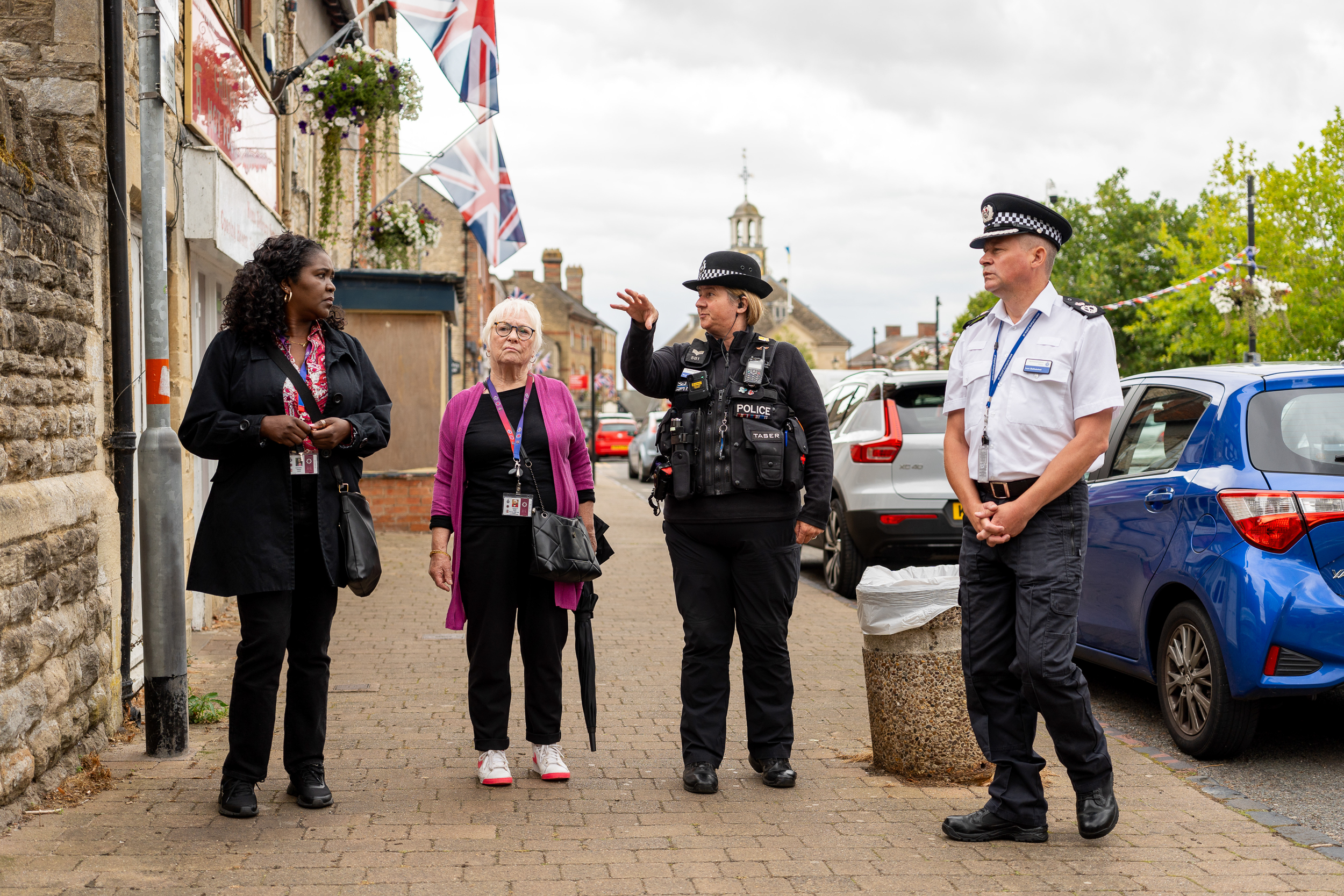 DPFCC Marianne Kimani, PFCC Danielle Stone and Chief Constable Ivan Balhatchet talking to a police officer in Brackley town centre