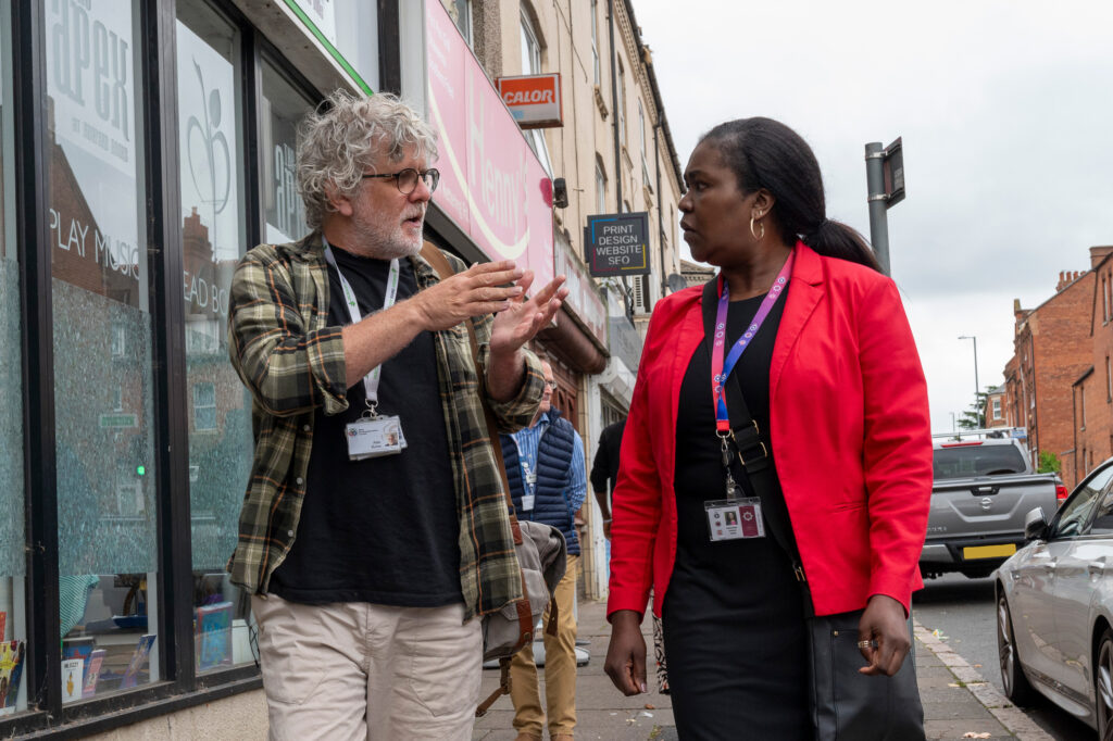 Deputy Police Fire and Crime Commissioner Marianne Kimani wearing a red blazer talks with Community Cohesion Offer Alan Burns