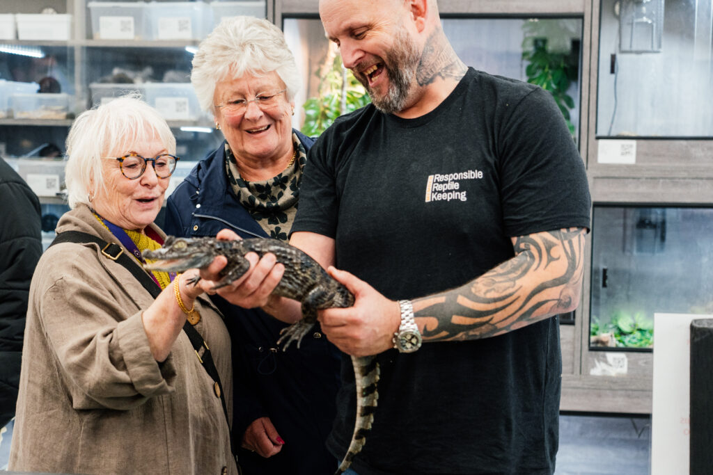 PFCC Danielle Stone standing with Rushden Town Councillor Marion Holloman and owner of House of Venom reptile shop, holding a young crocodile