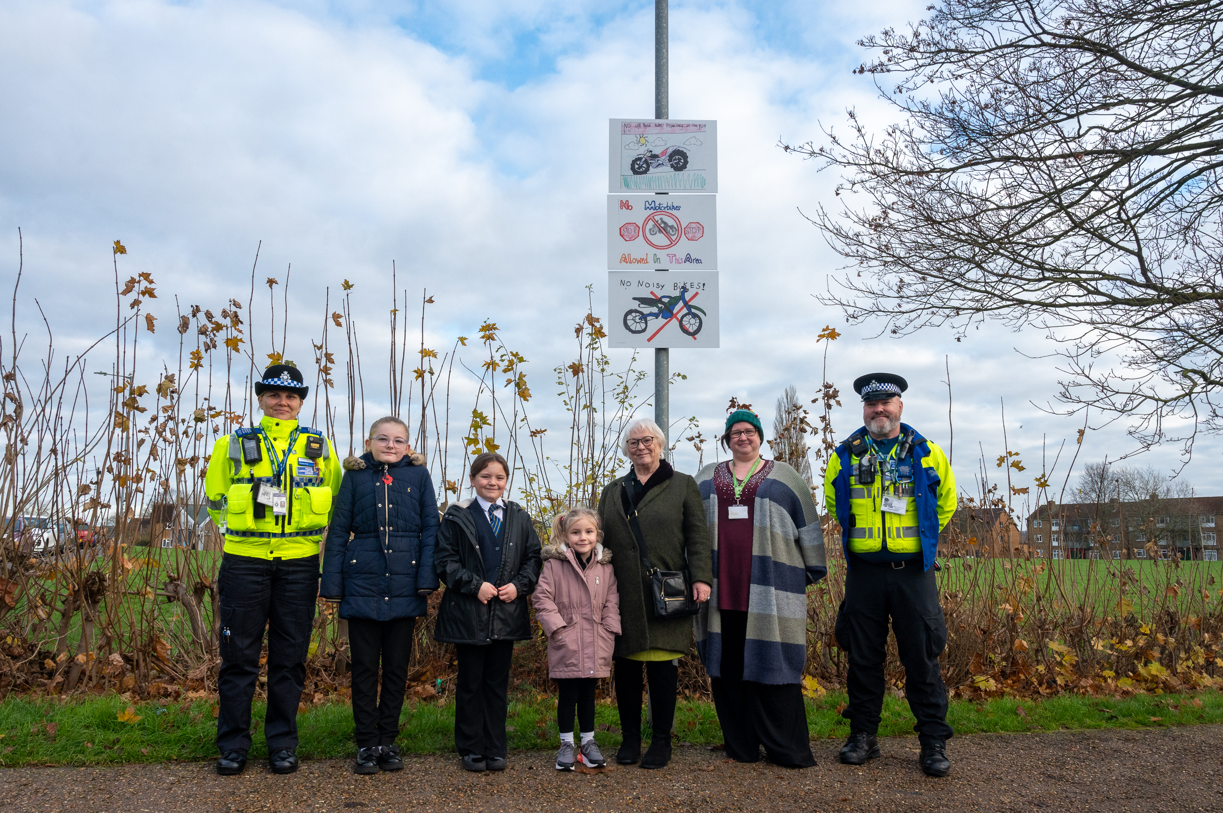 A line up of people featuring PFCC Danielle Stone, Two PCSO, Three School children and a headteacher in front of the winning signs