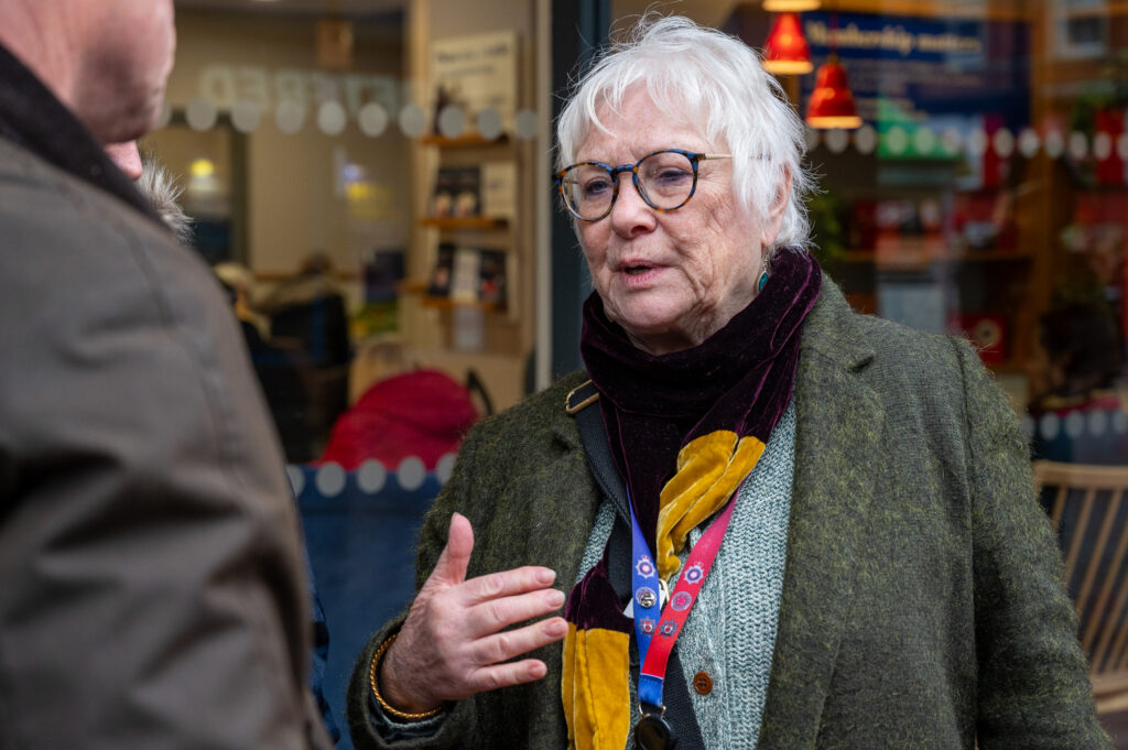 Police Fire and Crime Commissioner Danielle Stone, wearing a green coat and black scarf, is pictured outside the glass facade of a shop in Wellingborough town centre.