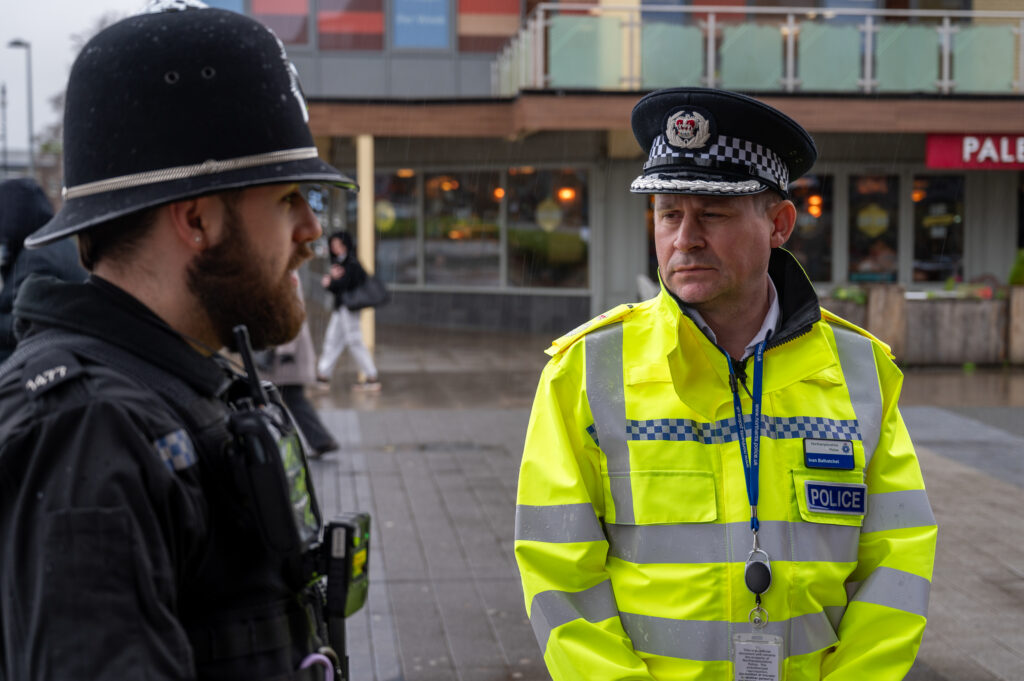 CC Ivan Balhatchet wearing fluorescent police jacket speaks to neighbourhood police officer in Corby