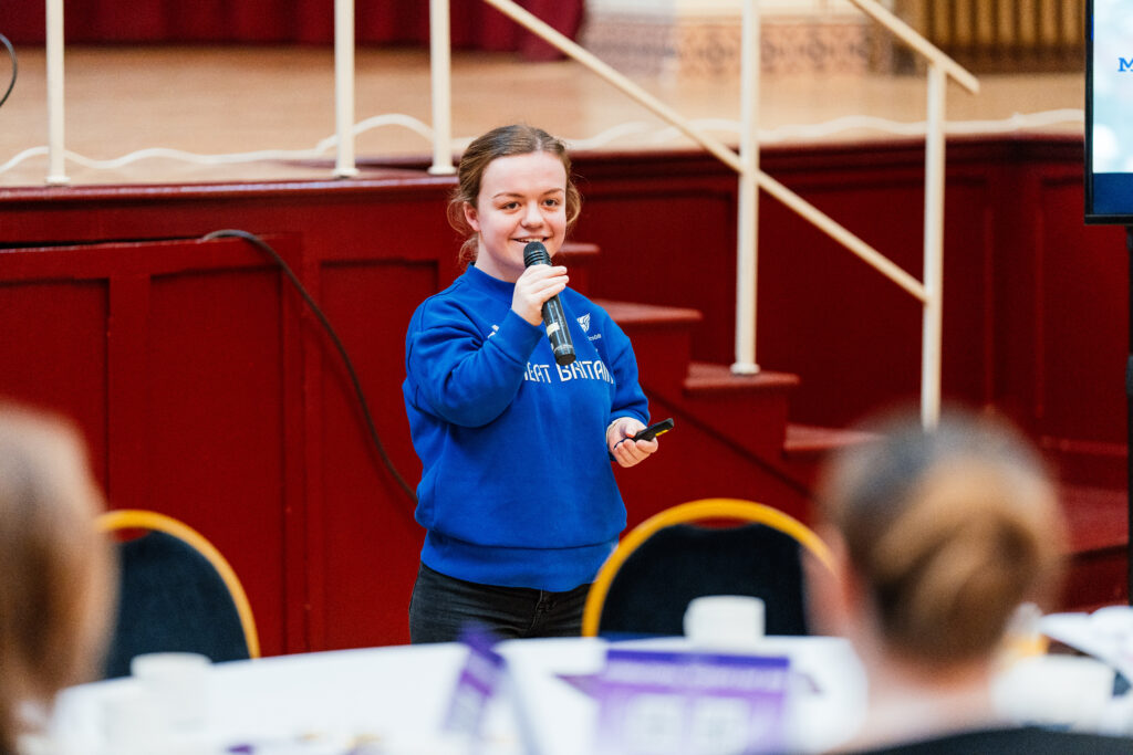 Paralympic gold medallist Maisie Summers-Newton wearing a blue sweatshirt speaks to the room 