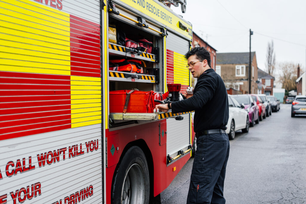 NFRS prevention team member is stood next to a fire engine