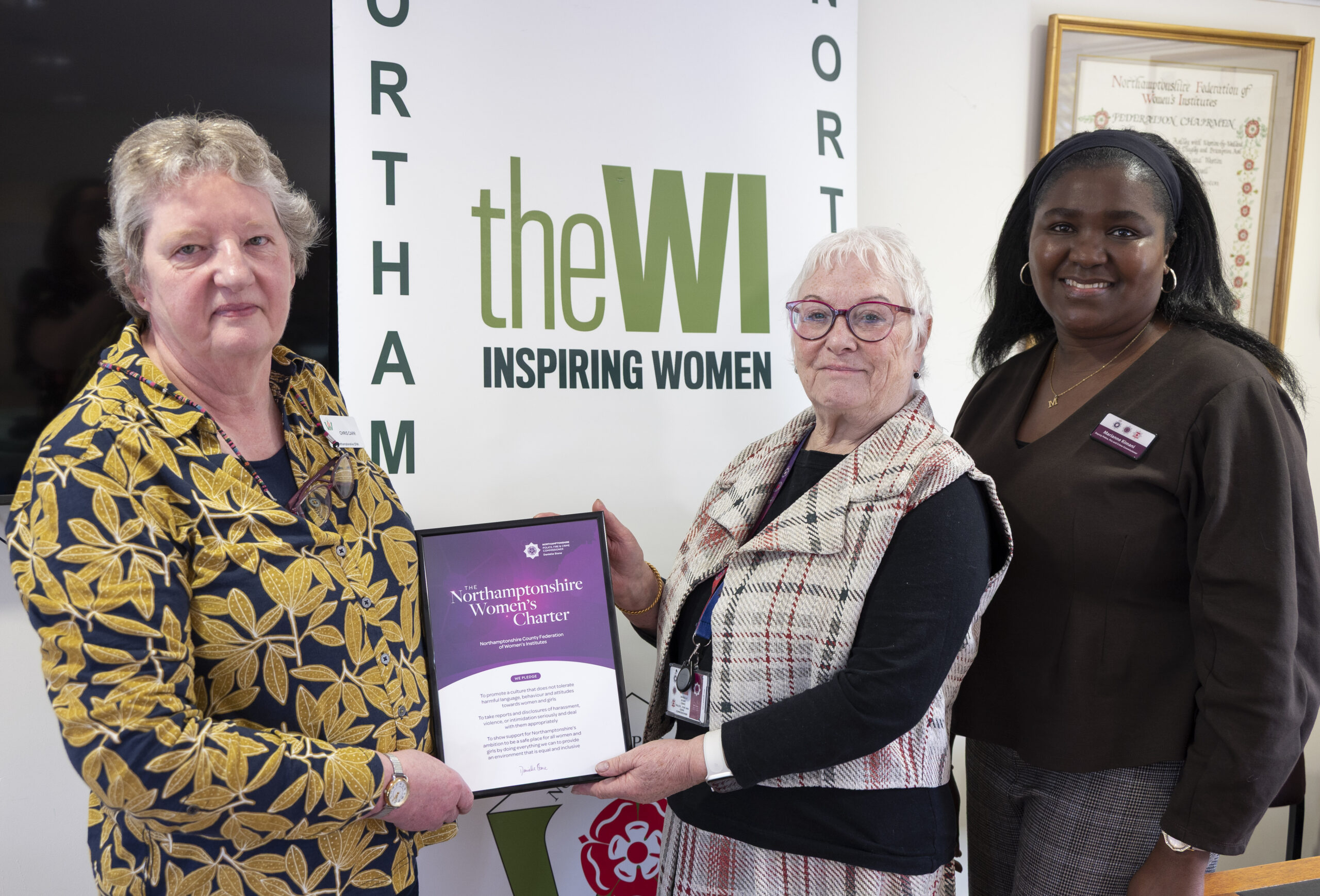 3 people in front of a banner with a certificate